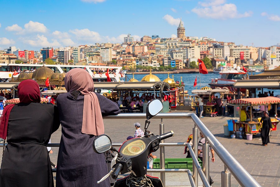 Muslim women looking Istanbul panorama with Galata tower . Istanbul, Turkey.